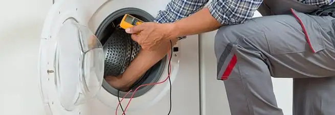 Dryer repair technician inspecting and repairing a clothes dryer in Fort Wayne, IN
