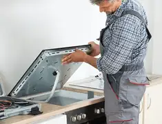 Appliance repair technician installing a built-in cooktop in Fort Wayne, IN