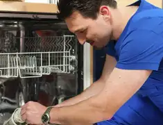 Dishwasher repair technician inspecting and servicing an open dishwasher in Fort Wayne, IN