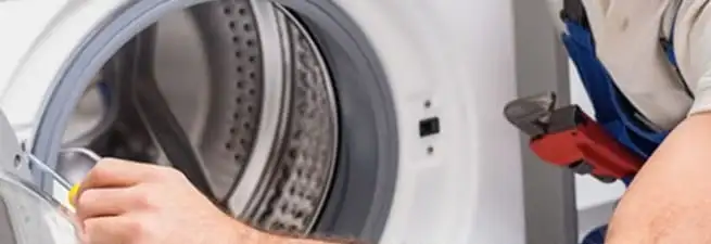 Appliance technician repairing a clothes dryer drum and internal parts in Fort Wayne, IN