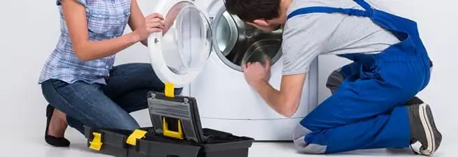 Washer repair technician inspecting a front-load washing machine with tools in Fort Wayne, IN
