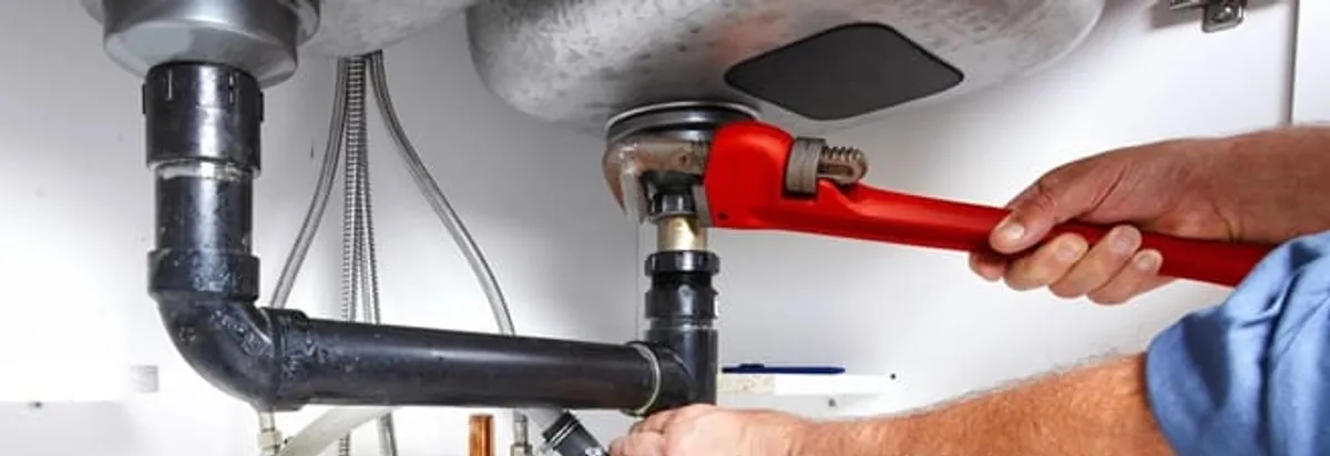 Garbage disposal repair technician tightening the sink drain and disposal connection in Fort Wayne, IN