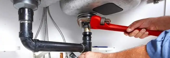 Garbage disposal repair technician tightening the sink drain and disposal connection in Fort Wayne, IN