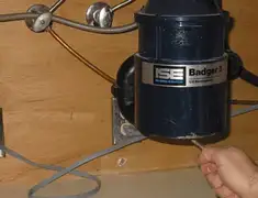 Garbage disposal repair technician tightening the mounting ring under a sink in Fort Wayne, IN