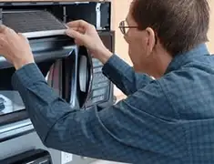Appliance repair technician replacing a microwave vent filter in Fort Wayne, IN