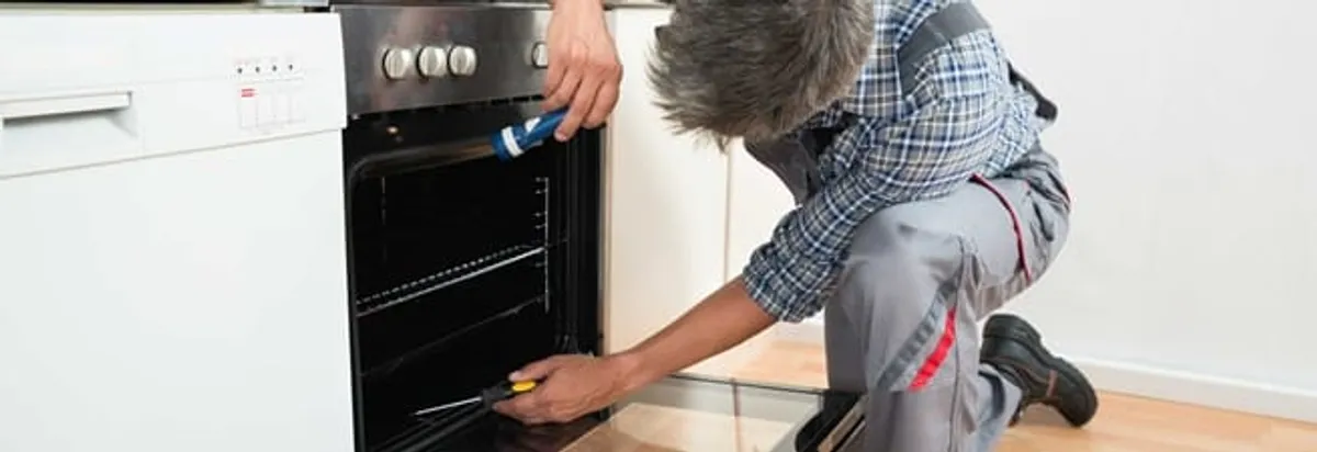 Oven repair technician inspecting and servicing an electric oven in Fort Wayne, IN