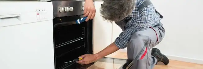 Oven repair technician inspecting and servicing an electric oven in Fort Wayne, IN