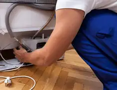 Appliance repair technician fixing refrigerator water line and connections in Fort Wayne, IN