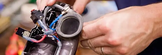Vacuum repair technician reconnecting wiring and components in Fort Wayne, IN