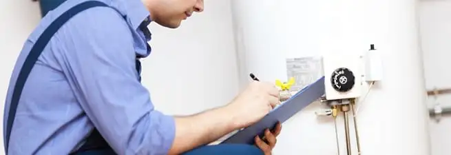 Water heater repair technician inspecting the unit and recording service notes in Fort Wayne, IN