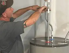 Water heater repair technician tightening supply line connections in Fort Wayne, IN