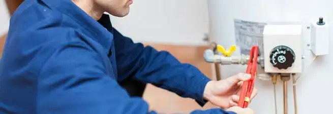 Water heater repair technician adjusting the temperature control and gas valve in Fort Wayne, IN